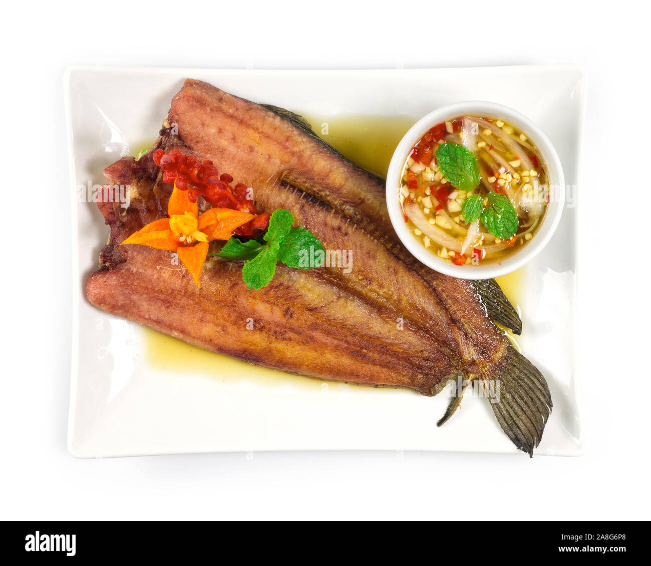 Gebratener Fisch in Sauce Fisch und Meeresfrüchte Thai Stil Soße dekorieren mit geschnitzten chili Draufsicht Stockfoto