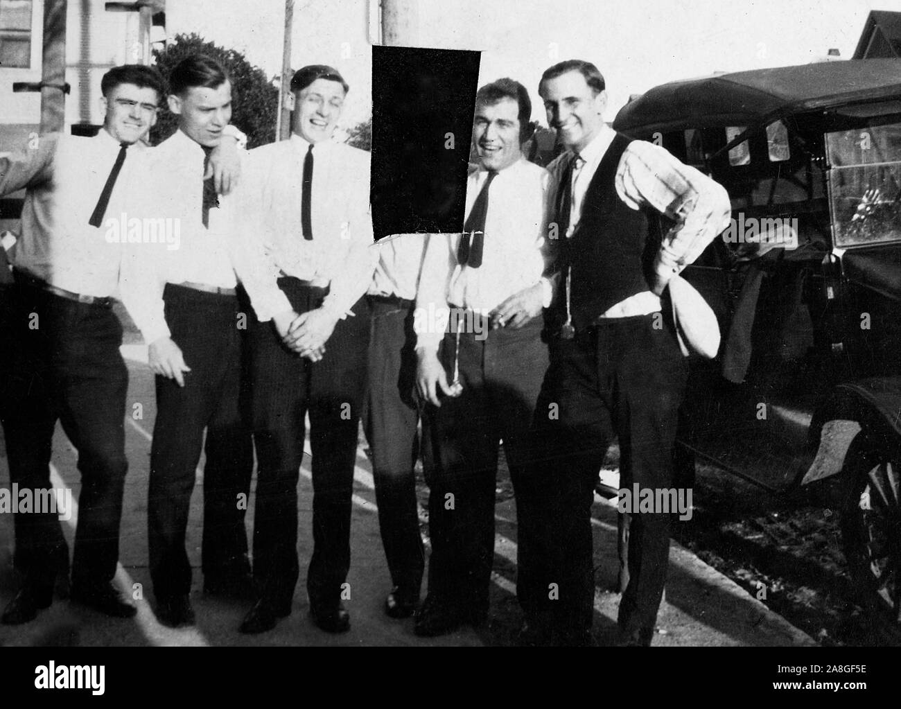 Eine Momentaufnahme zeigt eine Gruppe von Freunden, die durch einen Punkt Auto posiert mit einem von ihnen anschließend aus dem Foto von einer wahrscheinlichen wütend ex - Freundin oder ex-Frau, Ca in Scheiben geschnitten. 1928. Stockfoto