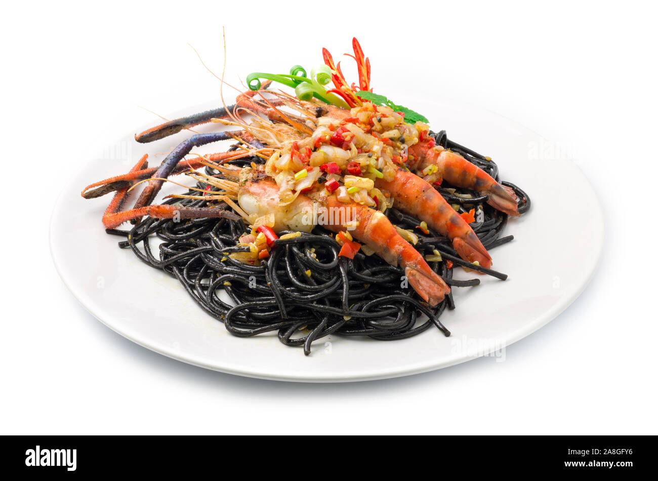 Schwarze Spaghetti scharfes Essen serviert mit gegrillten Garnelen Thai Food Gemischte italienische Fusion Style dekorieren mit geschnitzten Paprika und Frühlingszwiebeln Seitenansicht Stockfoto