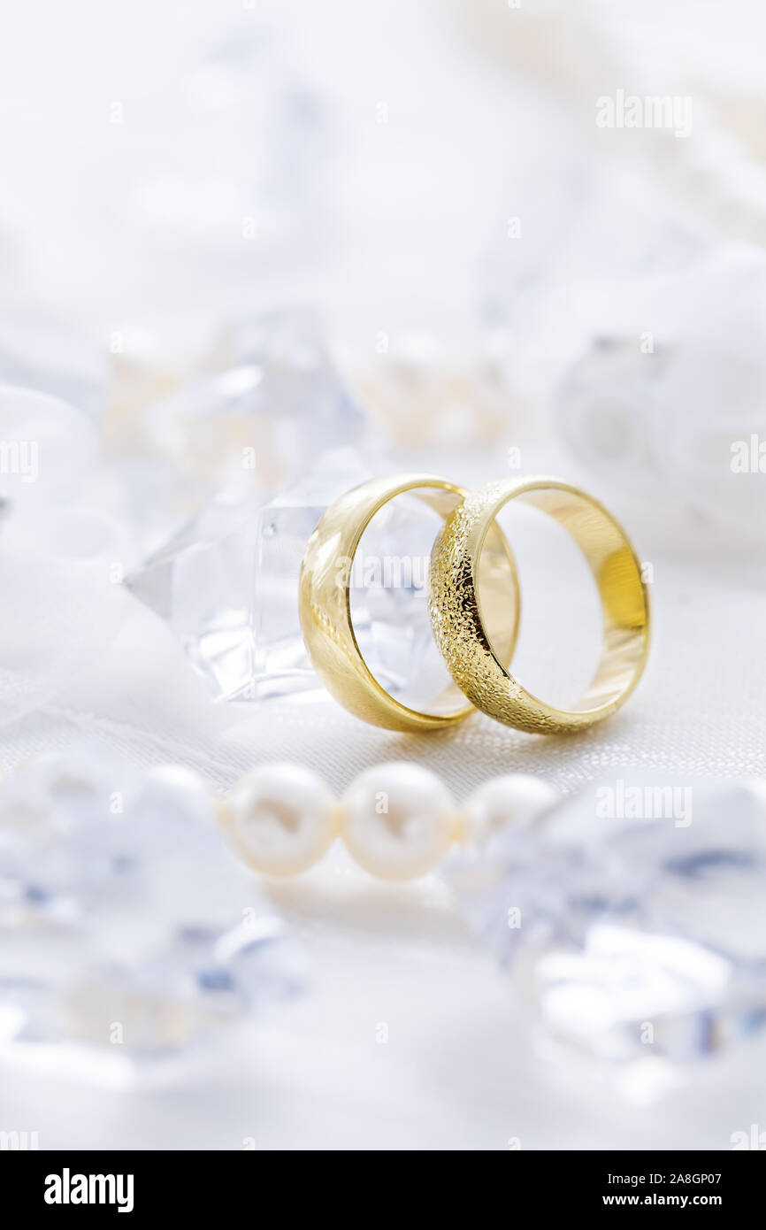 Zwei goldene Ringe mit Perlenkette und auf weißem Hintergrund als Symbol der Liebe und der Verbindung Stockfoto