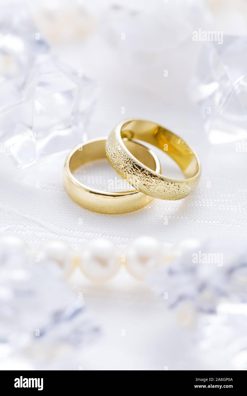 Zwei goldene Ringe mit Perlenkette und auf weißem Hintergrund als Symbol der Liebe und der Verbindung Stockfoto