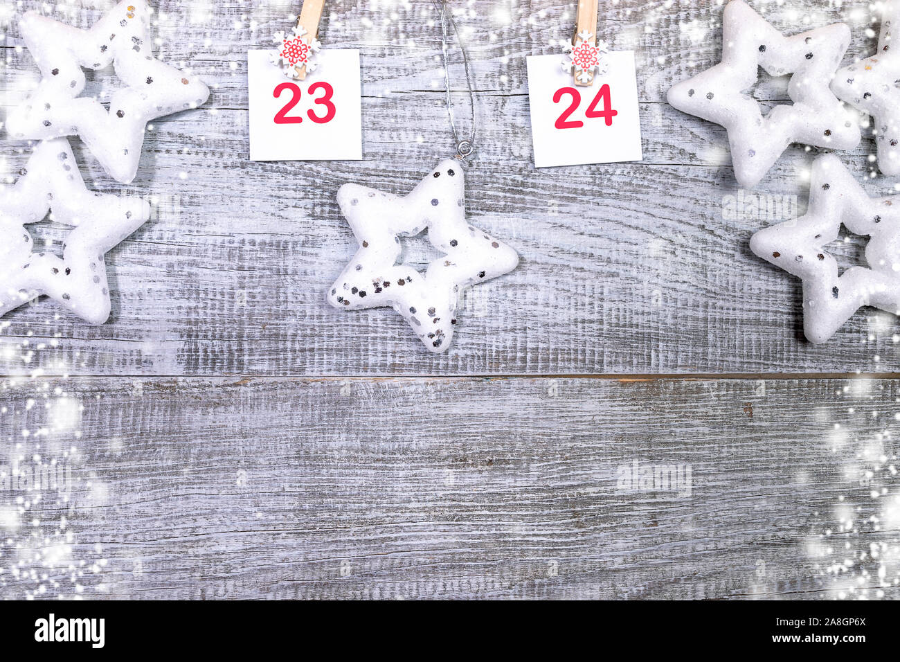 23-24 Teil der Adventskalender mit Blätter mit Zahlen auf dekorative Clips und weiße Weihnachten Spielzeug Sterne auf weißem Holz- snowy Hintergrund mit Kopieren s Stockfoto