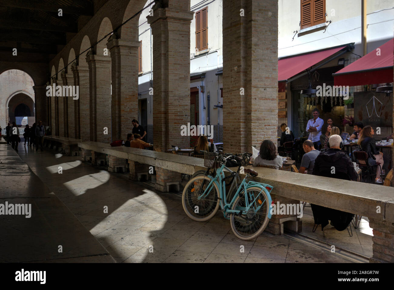Rimini, Italien, 20. Oktober 2019: Zwei Fahrräder vor kleines Café mit Kunden essen, trinken und unterhalten sich innerhalb der alten Fis entfernt geparkt Stockfoto