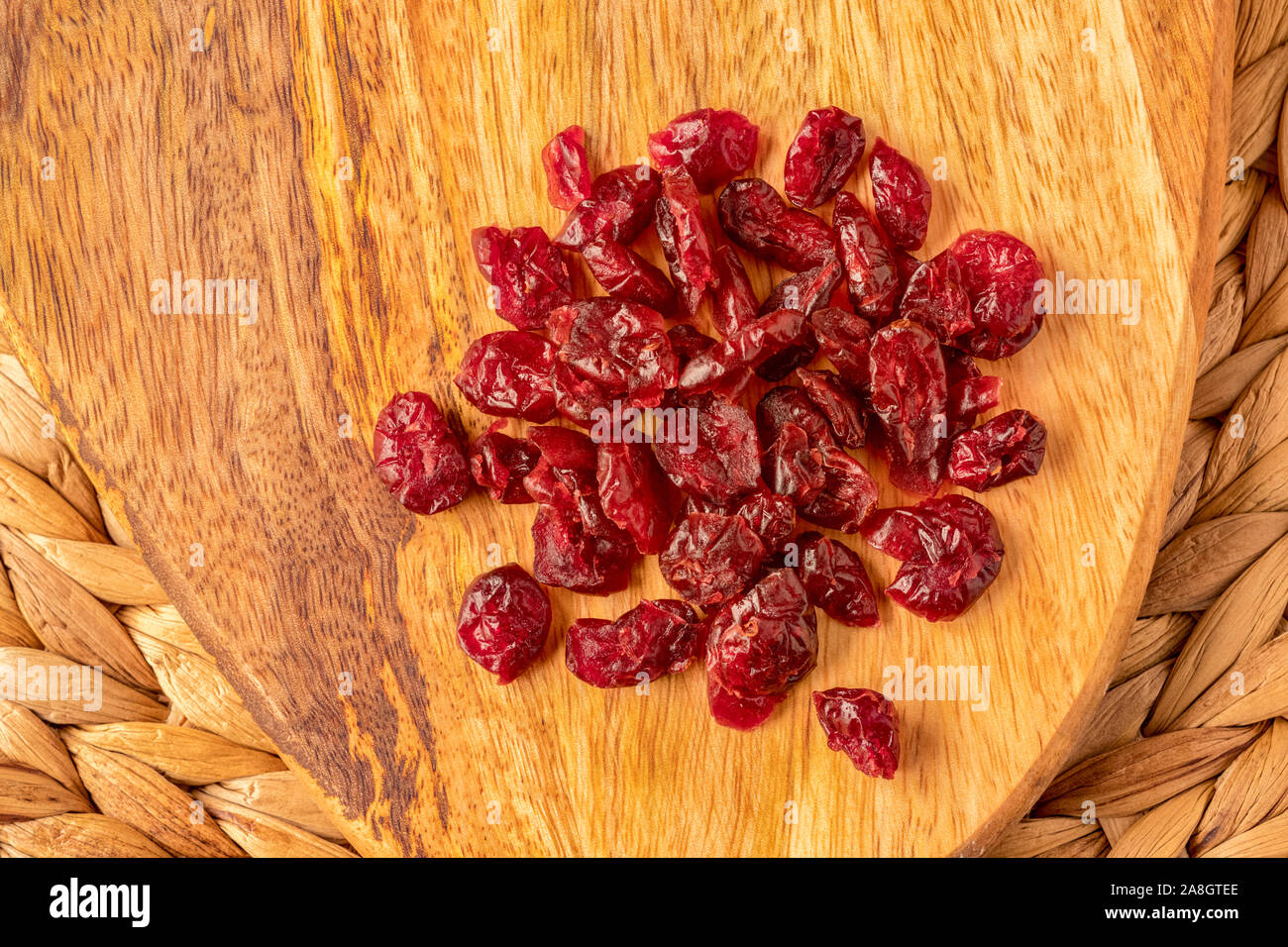 Getrocknete Cranberries auf einer Mango Holz Brett, einen gesunden Snack, in natürlichem Licht, front Fokus zu rücken, von oben. Stockfoto