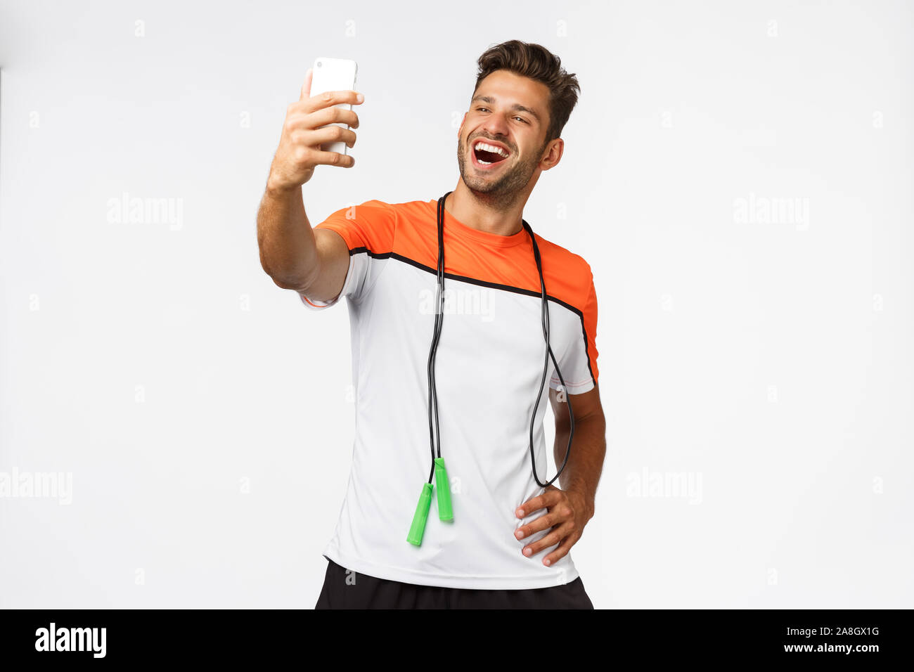 Stattlich, männlichen Athleten nehmen selfie nach dem Training im Fitnessraum, halten Smartphones mit verlängerter Arm und lächelt zufrieden und stolz, dass Anhänger neue Stockfoto