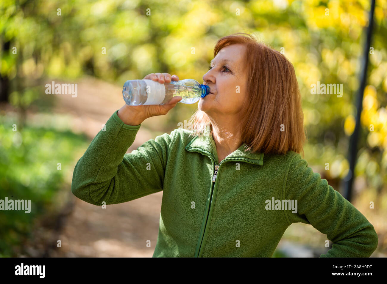 Ältere Frau ist Trinkwasser nach dem Training im Park. Stockfoto