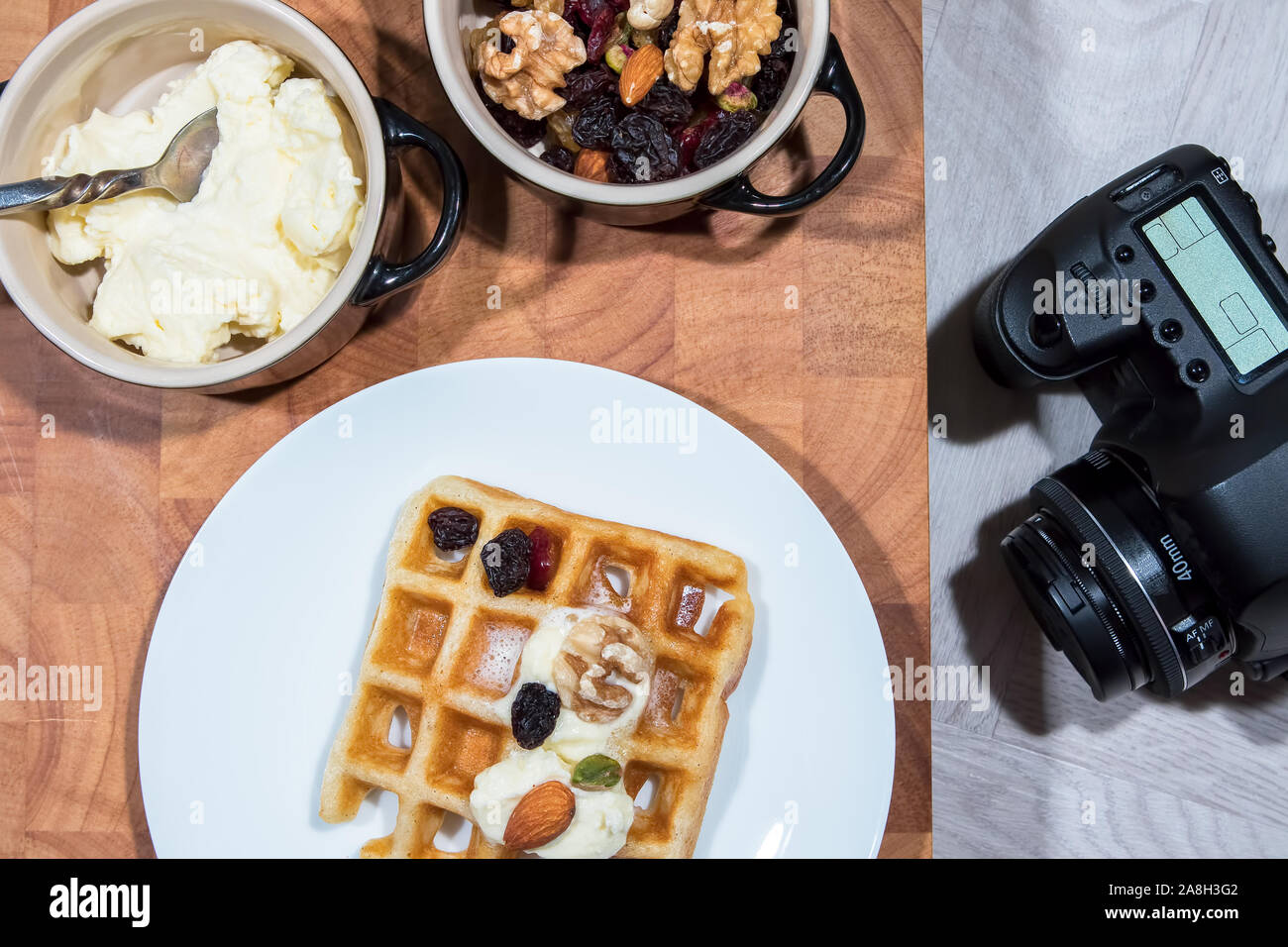 Flach essen Fotografie. Table Top frühstück Mahlzeit mit Kamera. Vorbereitung für ein Studio Foto schießen. Waffeln mit Obst Nüsse und Frische fettarme Sahne. Stockfoto