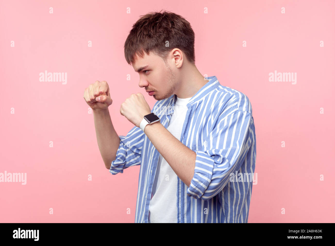 Porträt der jungen aggressiven braunhaarige Mann mit dem kleinen Bart und Schnurrbart in lässig-gestreiftes Hemd mit geballten Fäusten, bereit zu lochen, Atta Stockfoto