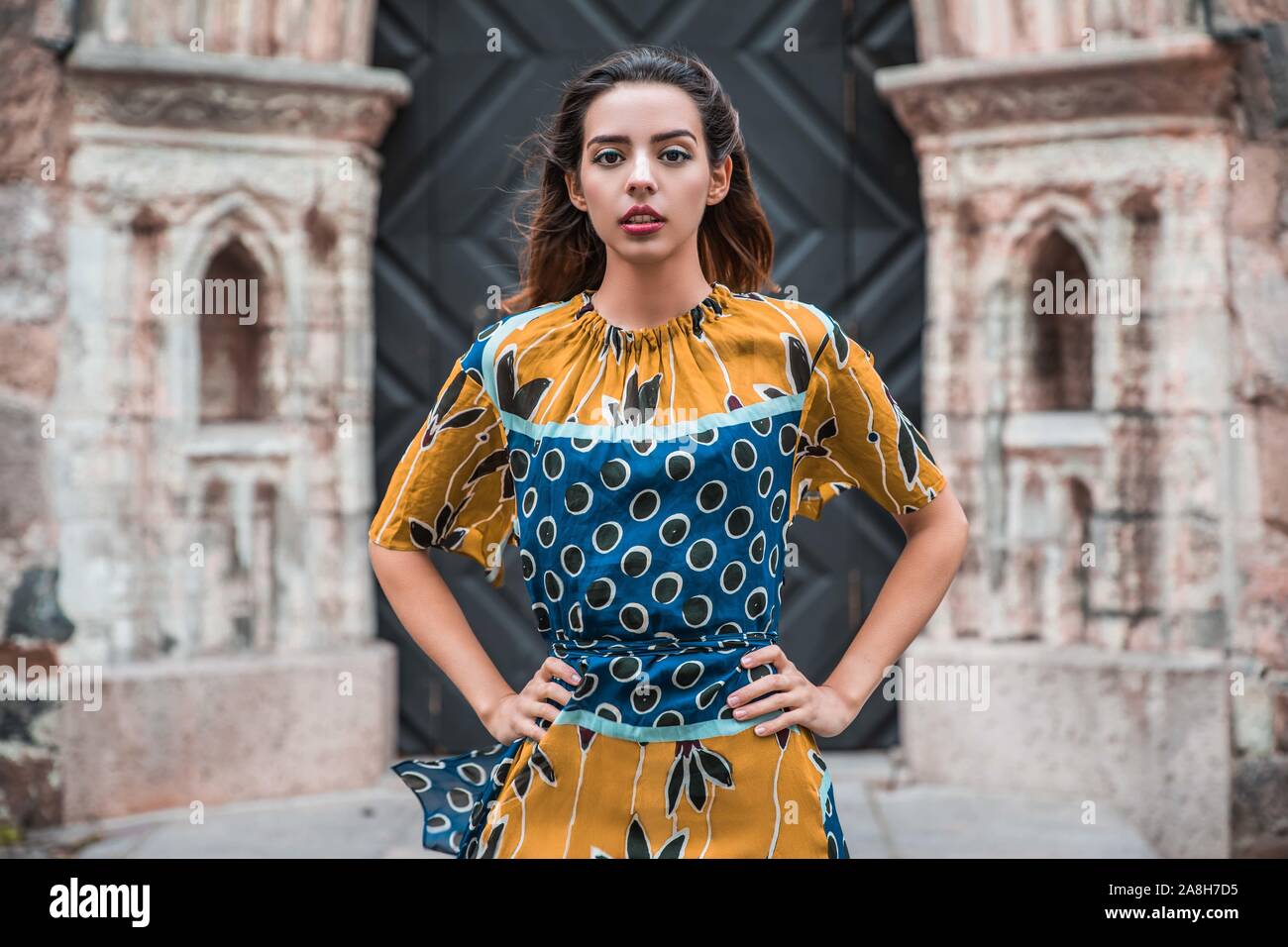 Schöne skinny albanische Mädchen posiert und zeigt die Orange Blue ornament Kleid Stockfoto