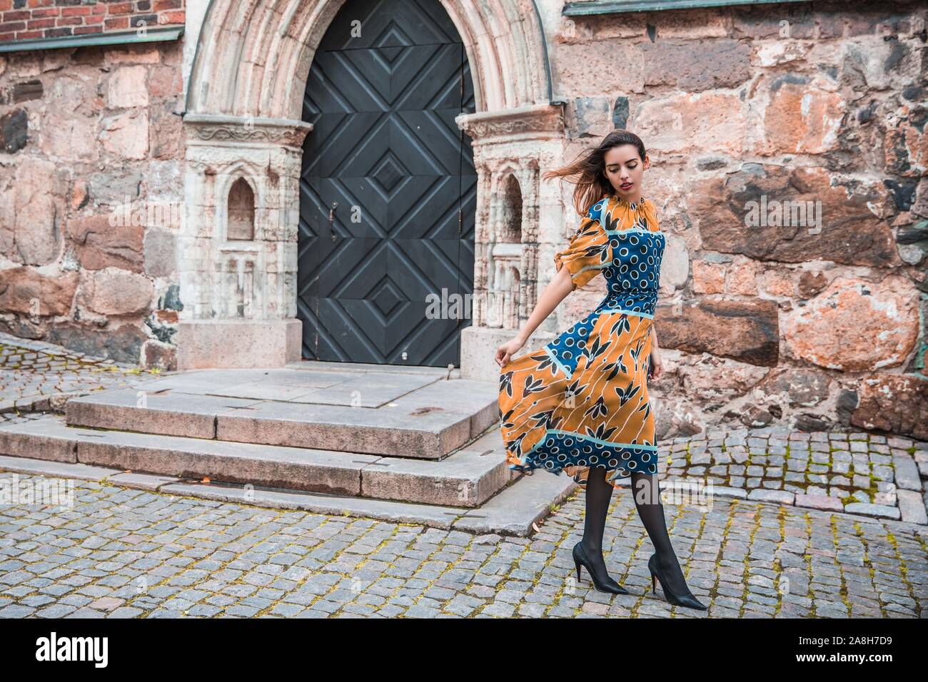 Schöne skinny albanische Mädchen posiert und zeigt die Orange Blue ornament Kleid Stockfoto