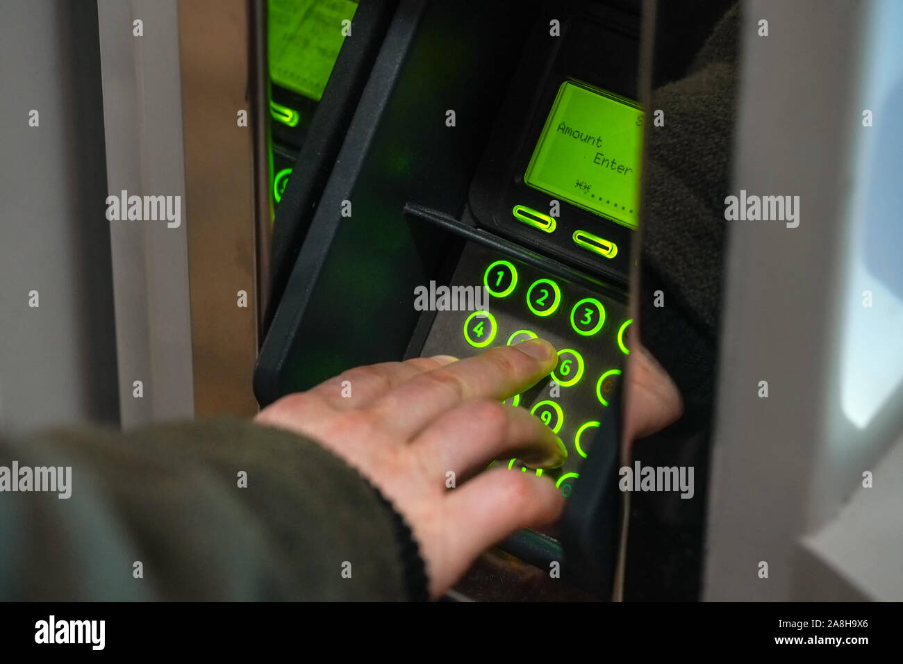 Mann über Geld von ATM/oben Travelcard zurückzutreten, Detail an den Fingern eingeben Betrag auf die grüne Klemme. Stockfoto
