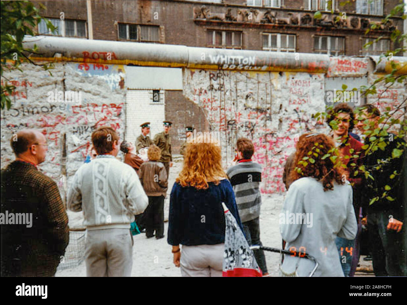 Michael Scott/Alamy Live Nachrichten - Berlin, Deutschland April 1990 - West Berliner Blick durch eine Lücke in der Berliner Mauer Richtung Osten deutsche Soldaten auf der anderen Seite. Im April 1990 fotografierte nur wenige Monate nach dem Fall der Berliner Mauer 1989 fiel. Stockfoto