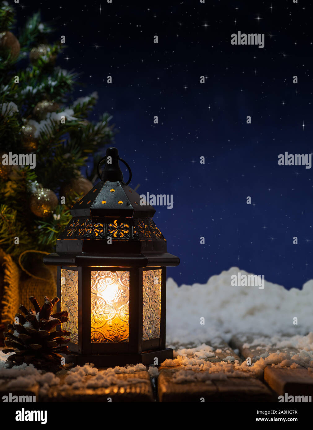 Leuchtende Laterne mit Weihnachtsbaum im Hintergrund unter einem Sternenhimmel Stockfoto