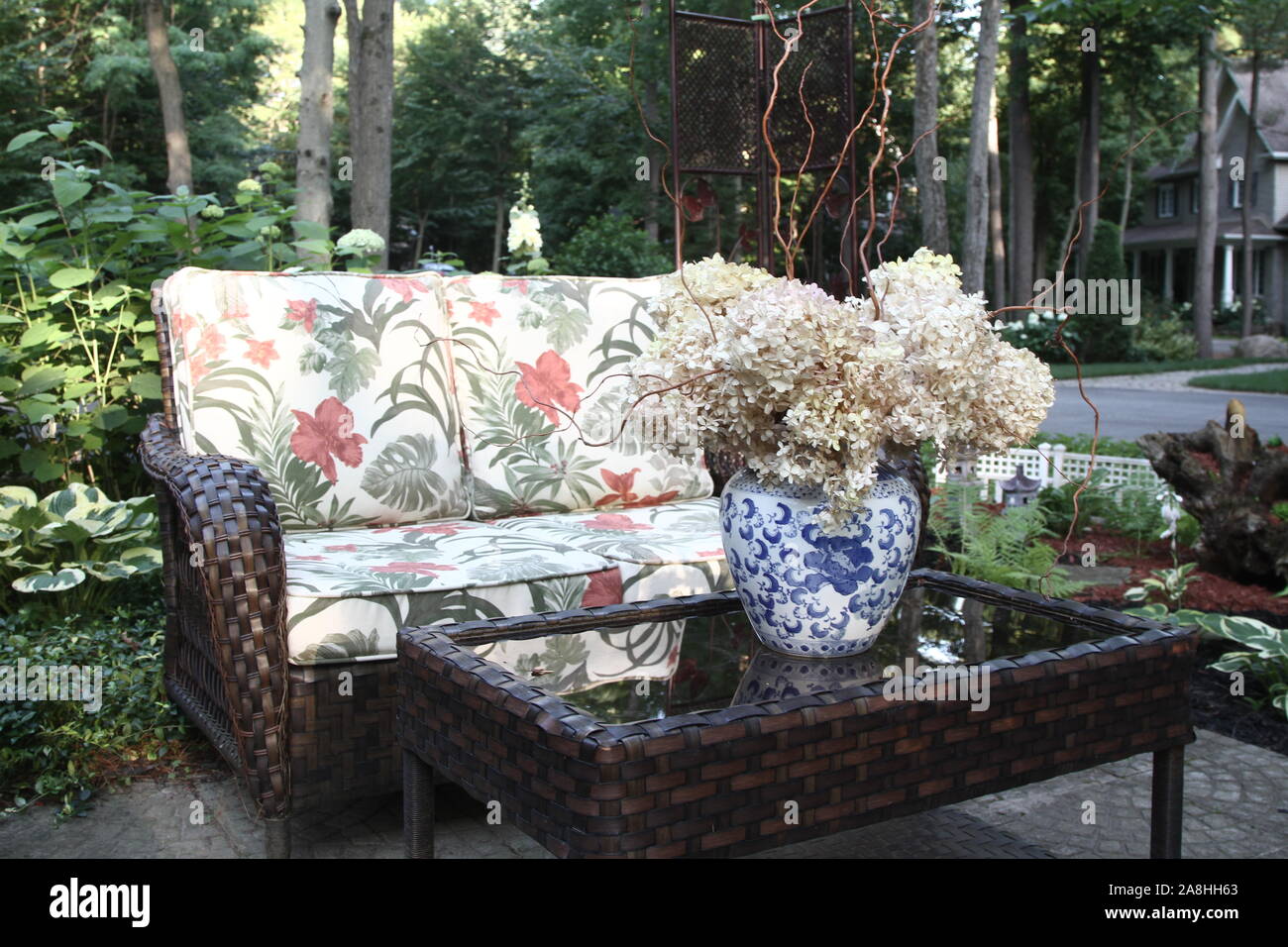 Outdoor Sitzgruppe mit Korbmöbeln, und eine Tabelle mit getrocknete Hortensien im Topf Stockfoto