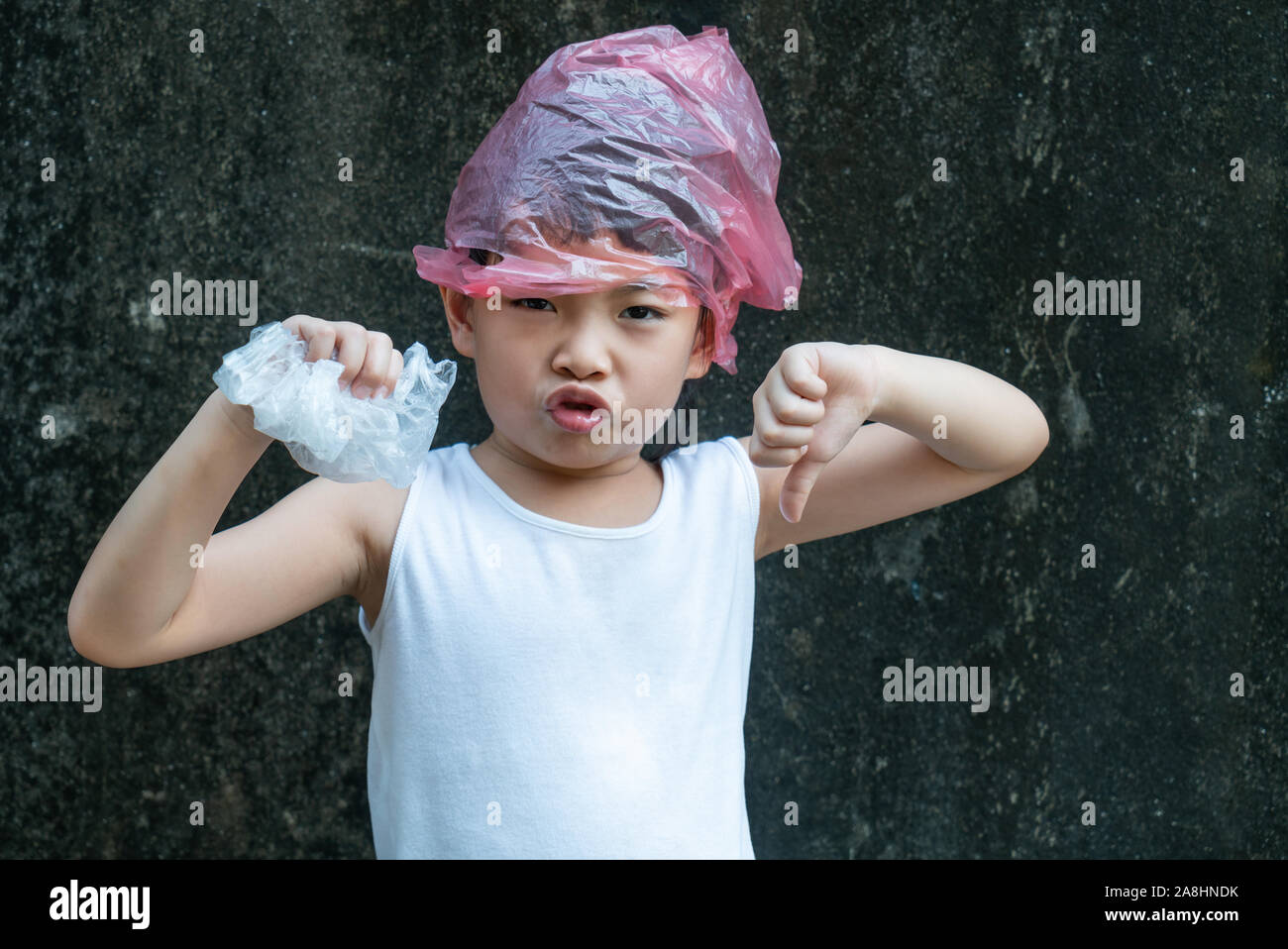 Niedliche kind Girl posiert mit Plastiktüten. Kunststoff ist auf ihrem Kopf. Konzept für die Anwendung von Plastikbeutel. Stockfoto