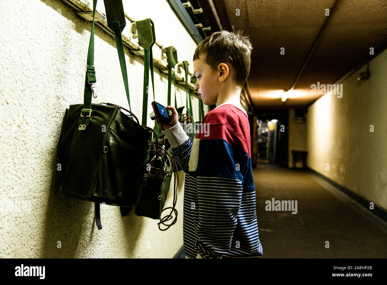 Ein Junge nimmt Bilder im Kelvedon Hatch secret Nuclear Bunker Eingang Tunnel. Altmodische Säcke und Radios an der Wand Stockfoto