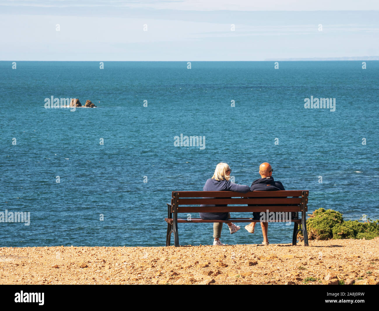 Zwei Leute schauen auf das Meer bei La Corbiere, Jersey, Channel Islands, Großbritannien. Stockfoto