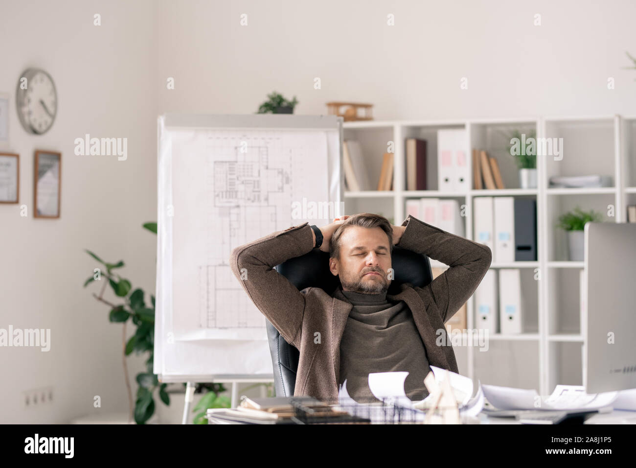 Reifen Büroangestellter in formale sitzt im Sessel mit Schreibtisch und entspannen Stockfoto