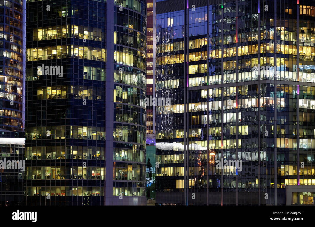 Wände aus Glas von modernen Bürogebäuden mit vielen großen Panoramafenstern in Downtown Business Cluster mit arbeitenden Menschen vordere Ansicht bei Nacht Stockfoto