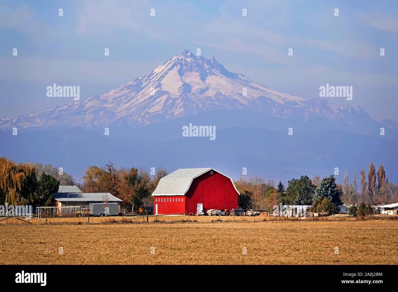 Eine helle rote Scheune auf einer Ranch unter den Hängen des Mount Jefferson, der zweithöchste Gipfel in Oregon, in zentralen Oregon in der Nähe der Stadt Madras. Stockfoto