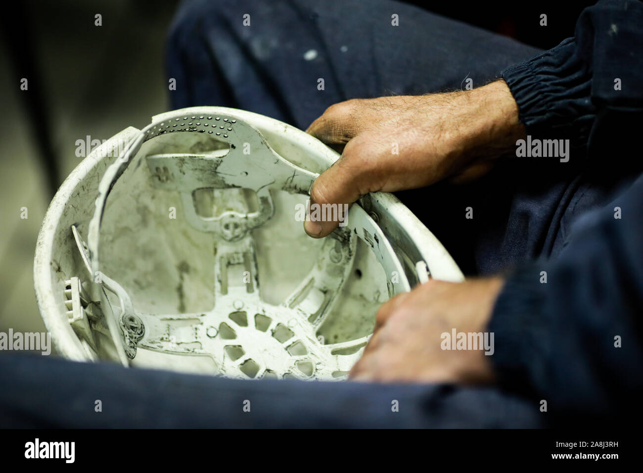 Details mit den Händen eines Fabrikarbeiters seinen schmutzigen Schutzhelm Holding. Stockfoto