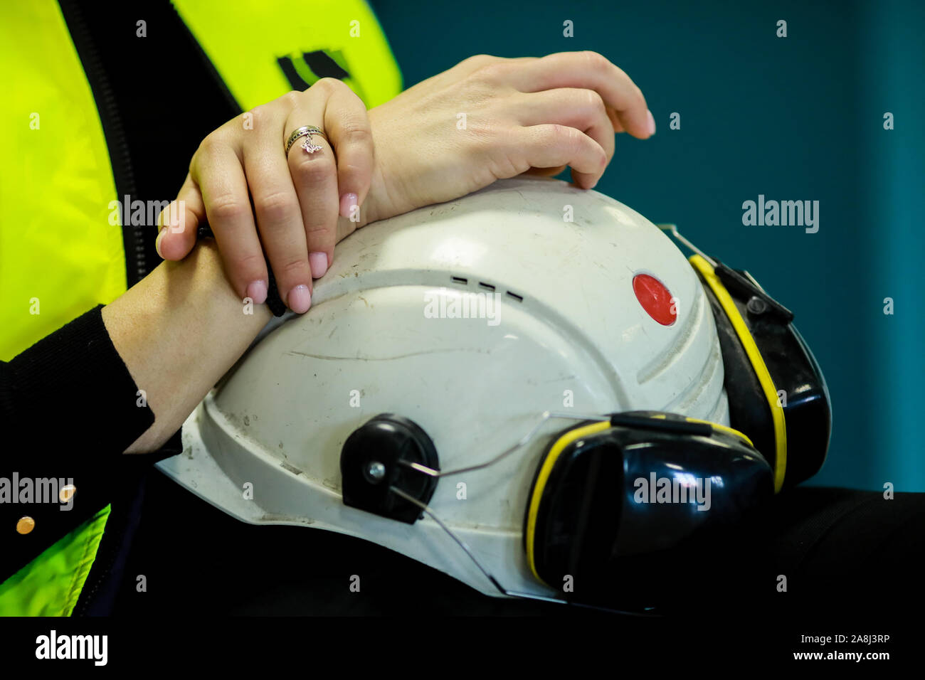 Details mit den Händen eines weiblichen Arbeiter ihren Schutzhelm und arbeiten Kopfhörer Holding. Stockfoto