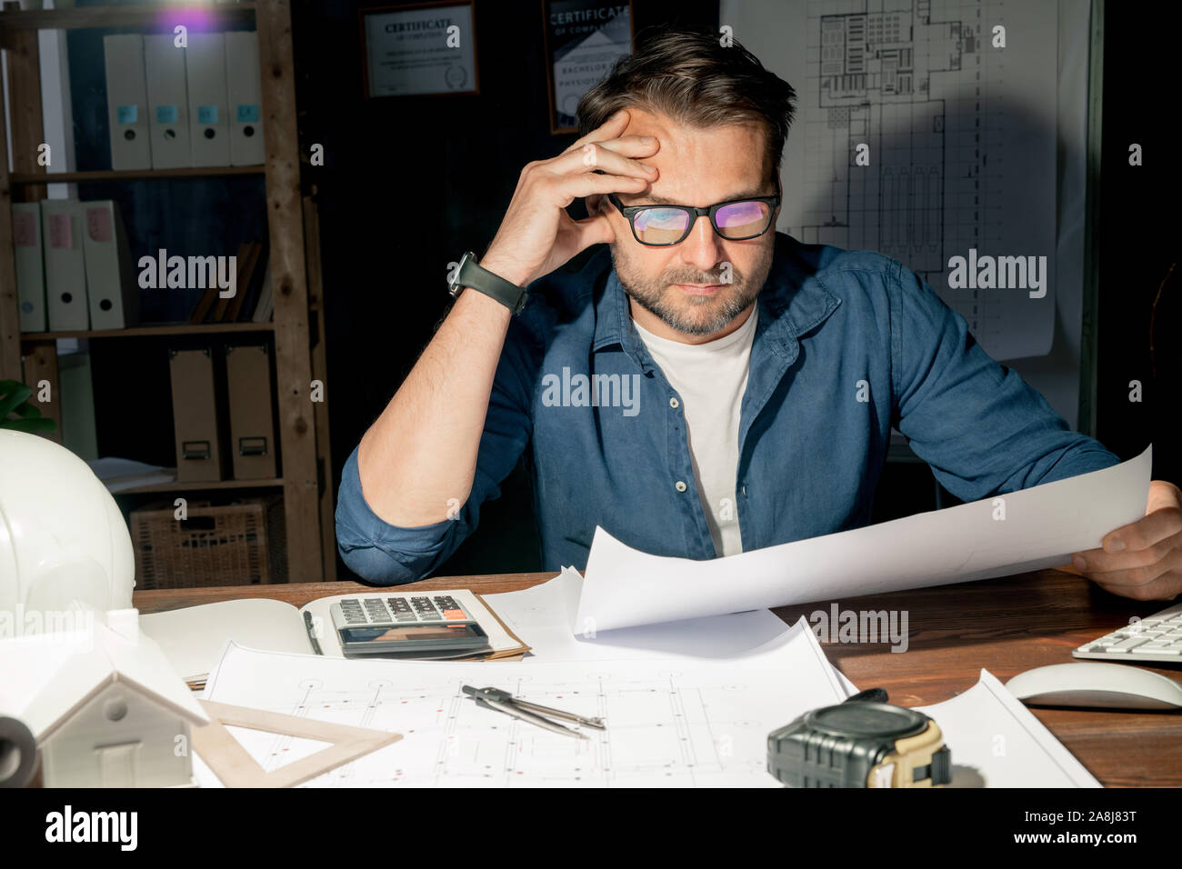 Schwere reifen Ingenieur in Brillen Kontrolle Skizze während spät Stockfoto