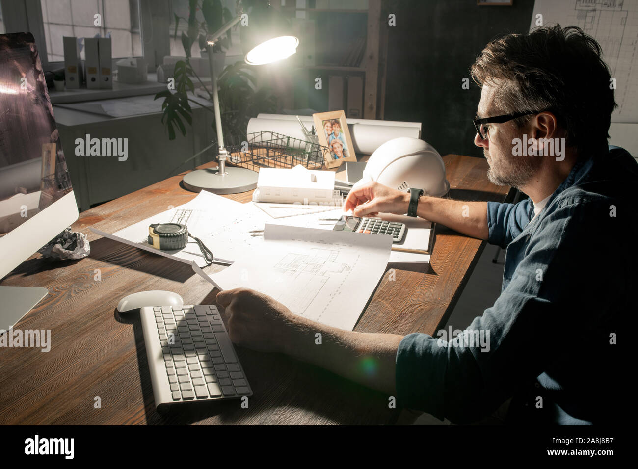 Moderne Techniker arbeiten mit Skizzen, während im Büro spät Stockfoto