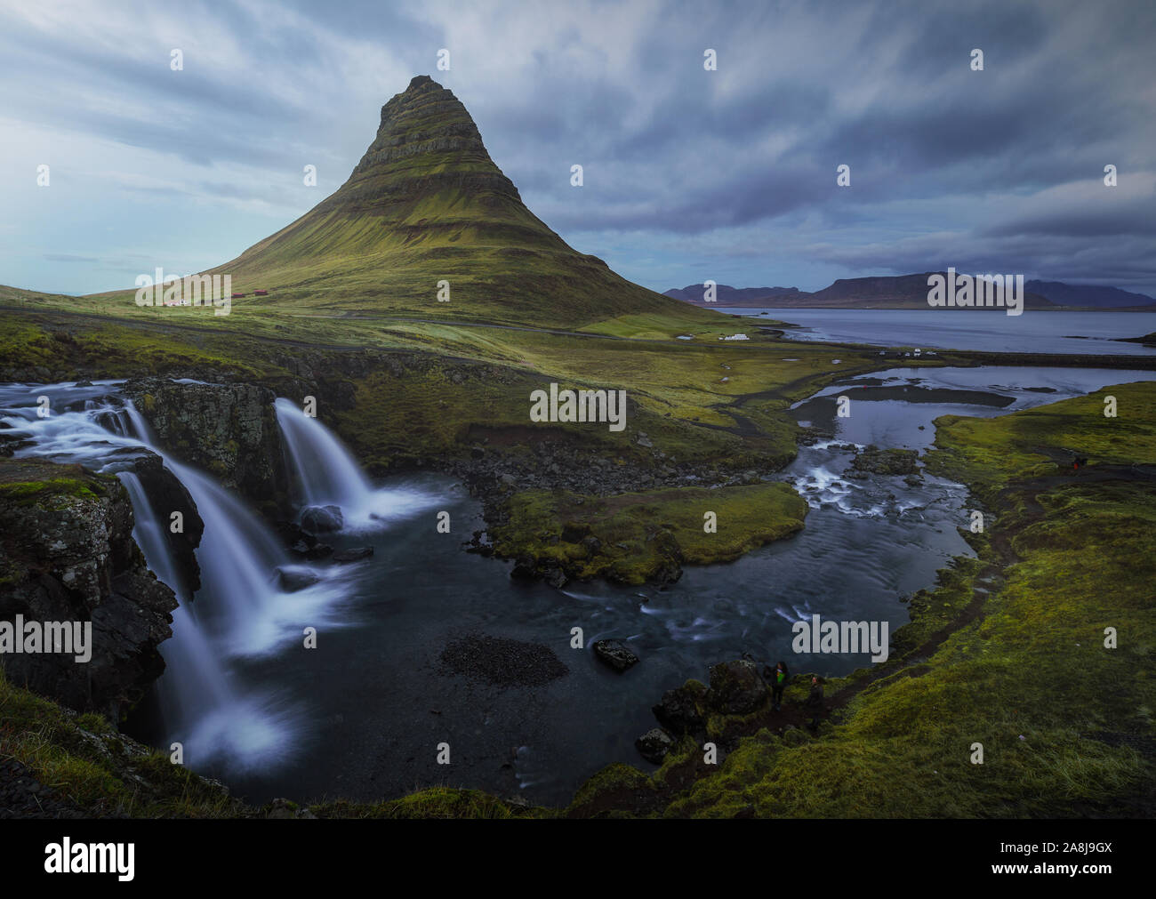 Kirkjufell, der berühmteste Berg Islands, Pfeil, Spiel der Throne Landschaft. Wasserfall, Fluss und eine Lagune, in der Nähe. Grüne Gras. Bewölkten Tag. Stockfoto
