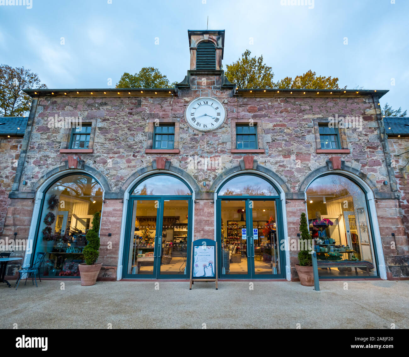 Restaurierung Yard Shop im Stall bei Dämmerung mit beleuchteten Fenstern, Dalkeith Country Park, Midlothian, Schottland, Großbritannien Stockfoto