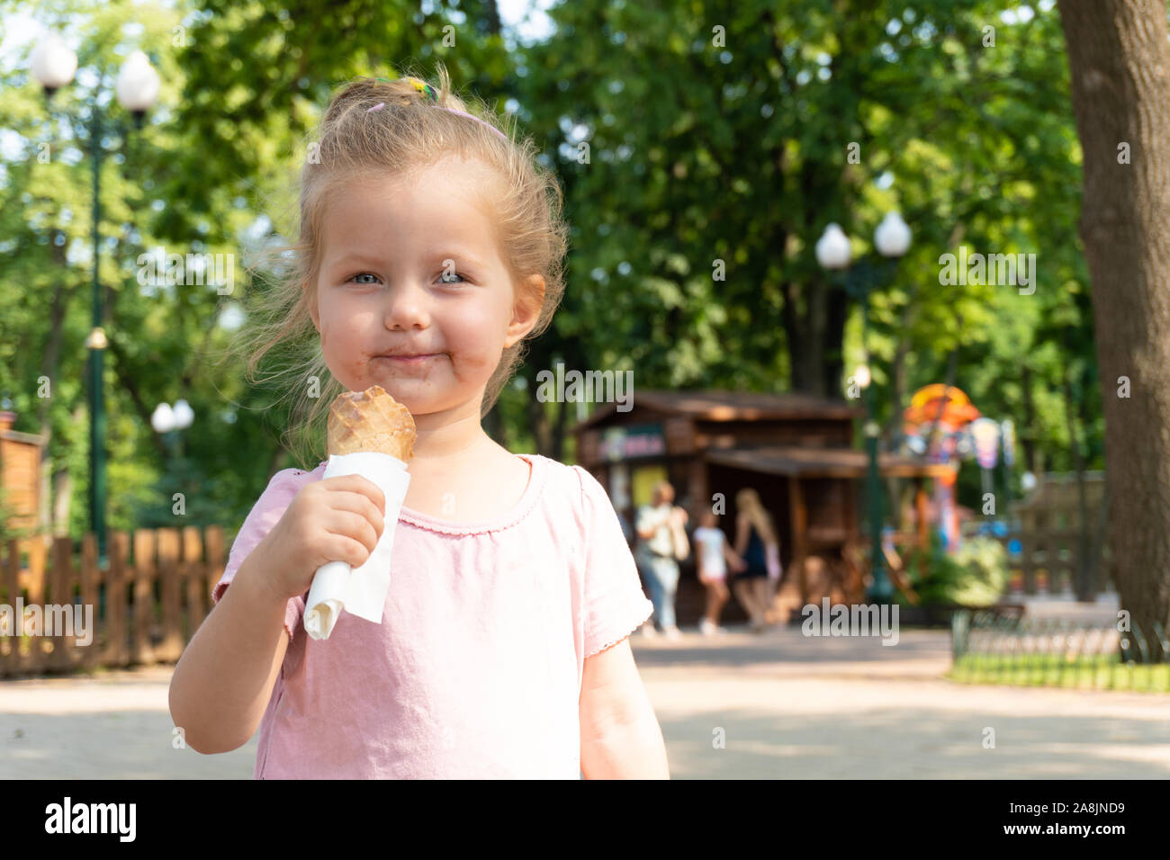 Lächelnde Mädchen isst ein Eis im Park Stockfoto