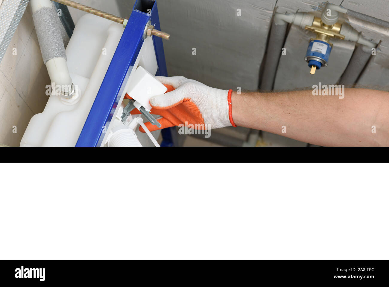 Ein Arbeitnehmer ist das Einfügen der Toilettenspülung Ventil in den eingebauten Tank. Ansicht von oben. Stockfoto