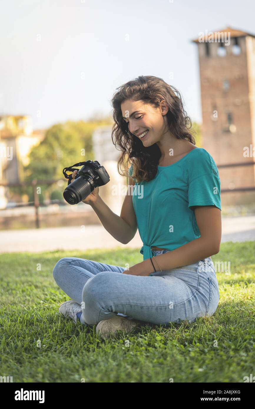 Fotograf Mädchen sitzen auf dem Gras an der Kamera Bildschirm schaut lächelnd Stockfoto