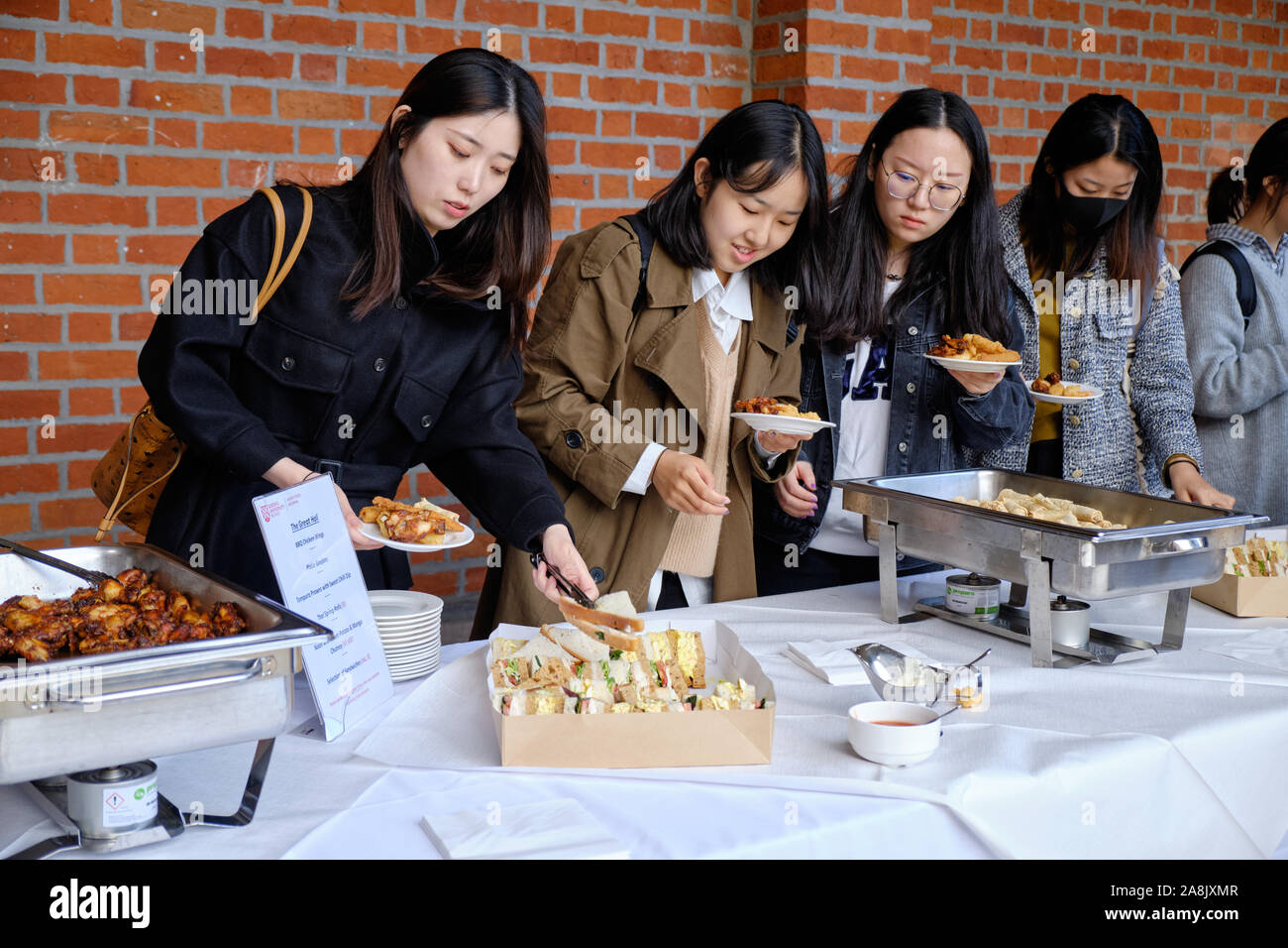 Ausländische Studierende erhalten Essen vom Buffet Catering in der Großen Halle der Queen's University in Belfast. Stockfoto