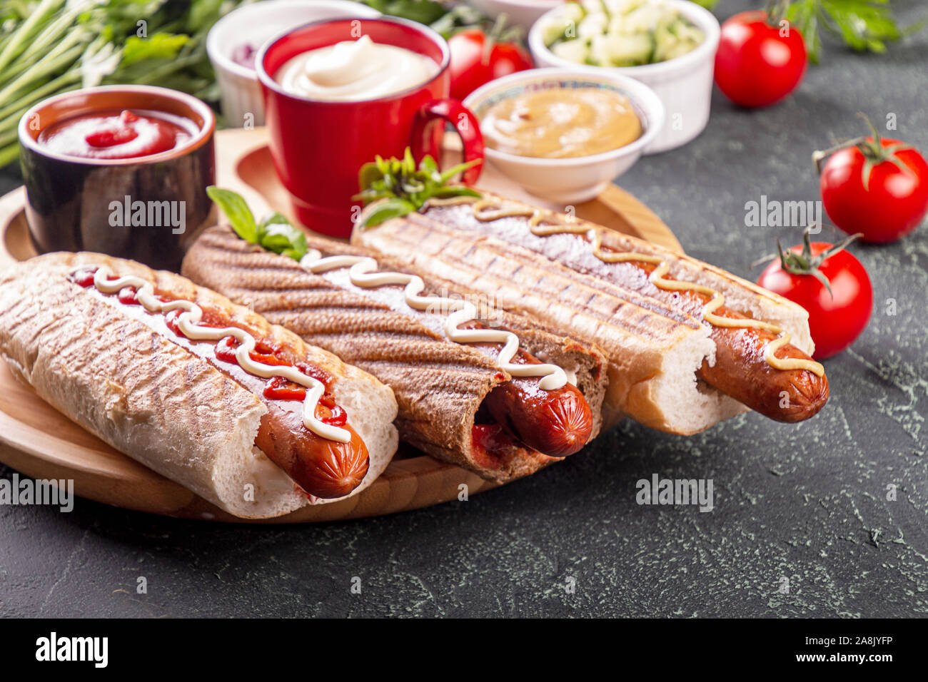 Hot Dogs, Gemüse und sauses auf schwarzem Hintergrund. Fast food, amerikanische tradditional Essen Stockfoto