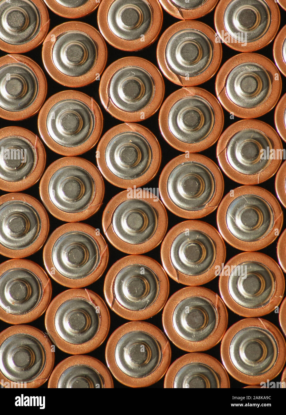 Hintergrundhintergrund der Batteriesäulen mit positiver Seite nach oben. Mehrere Akkus werden zu einem organisierten vertikalen Muster zusammengestapelt. Stockfoto