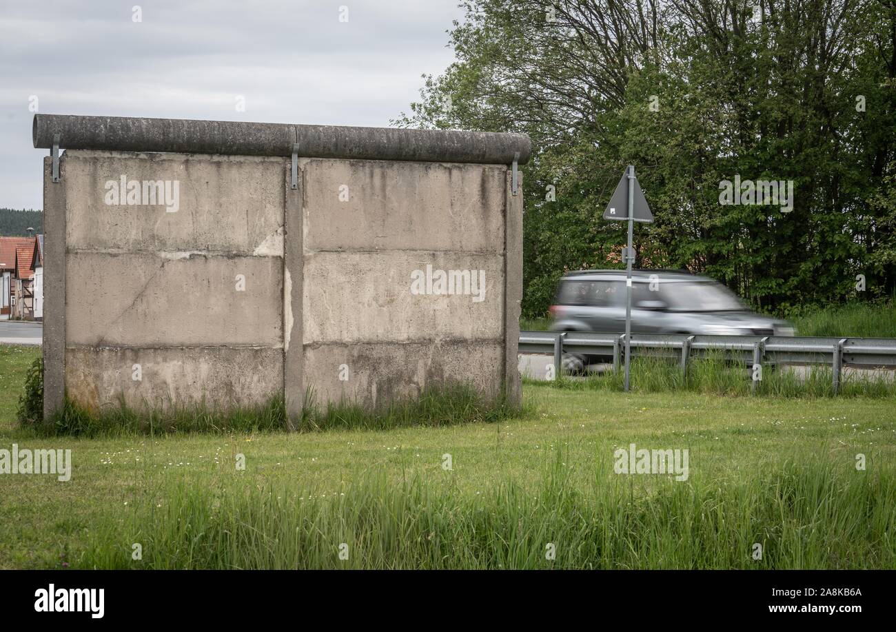 15. Mai 2019, Thüringen Großensee: ein Fahrzeug überquert die Straße an einem kleinen Stück Wand wie der Rest der DDR grenzbefestigung zwischen Großensee (l) in Thüringen und Kleinensee (r) in Hessen. Foto: Frank Rumpenhorst/dpa Stockfoto