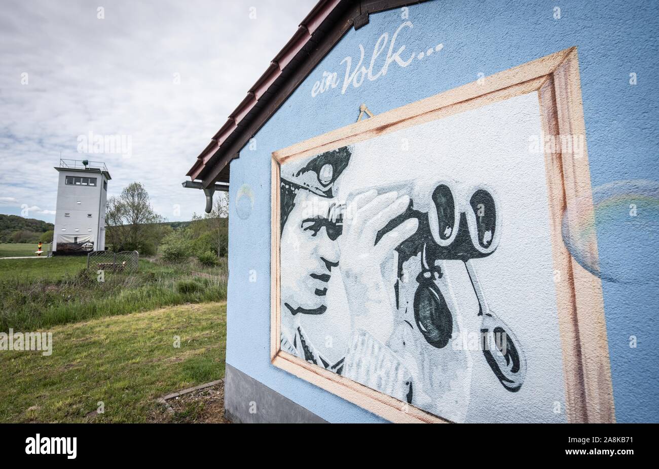 Vacha, Deutschland. 08 Nov, 2019. Eine alte Grenze Turm (l) wie der Rest der DDR Grenzbefestigung und ein Wandgemälde (r) zeigt einen DDR-Grenzsoldaten unter der Überschrift "Ein Volk" zwischen Vacha in Thüringen und Philippsthal in Hessen gesehen werden kann. Foto: Frank Rumpenhorst/dpa/Alamy leben Nachrichten Stockfoto