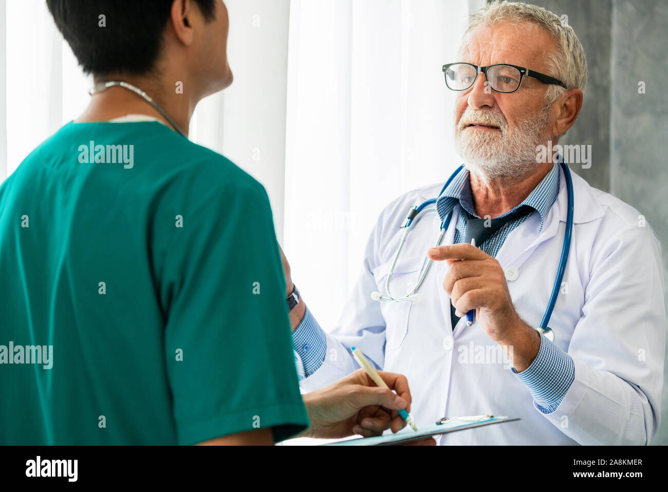 Älterer männlicher Arzt arbeiten mit einem anderen Arzt im Krankenhaus