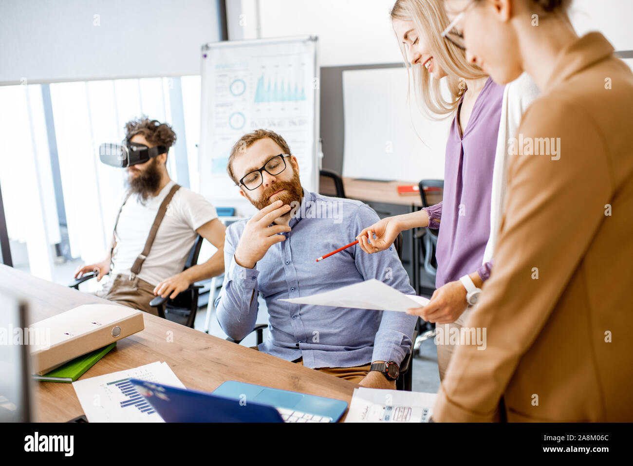 Gruppe von verschiedenen Kolleginnen und Kollegen, die im Büro, in der Diskussion oder eine kleine Konferenz am Arbeitsplatz Stockfoto
