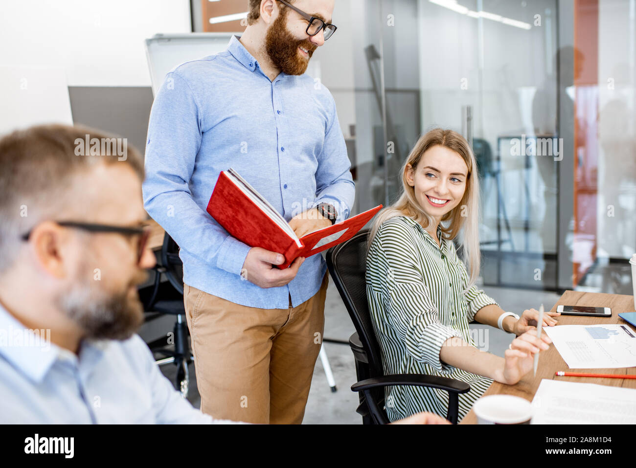 Junge Kolleginnen und Kollegen, die im Büro, die Diskussion über einen Arbeitsplatz mit Computer Stockfoto