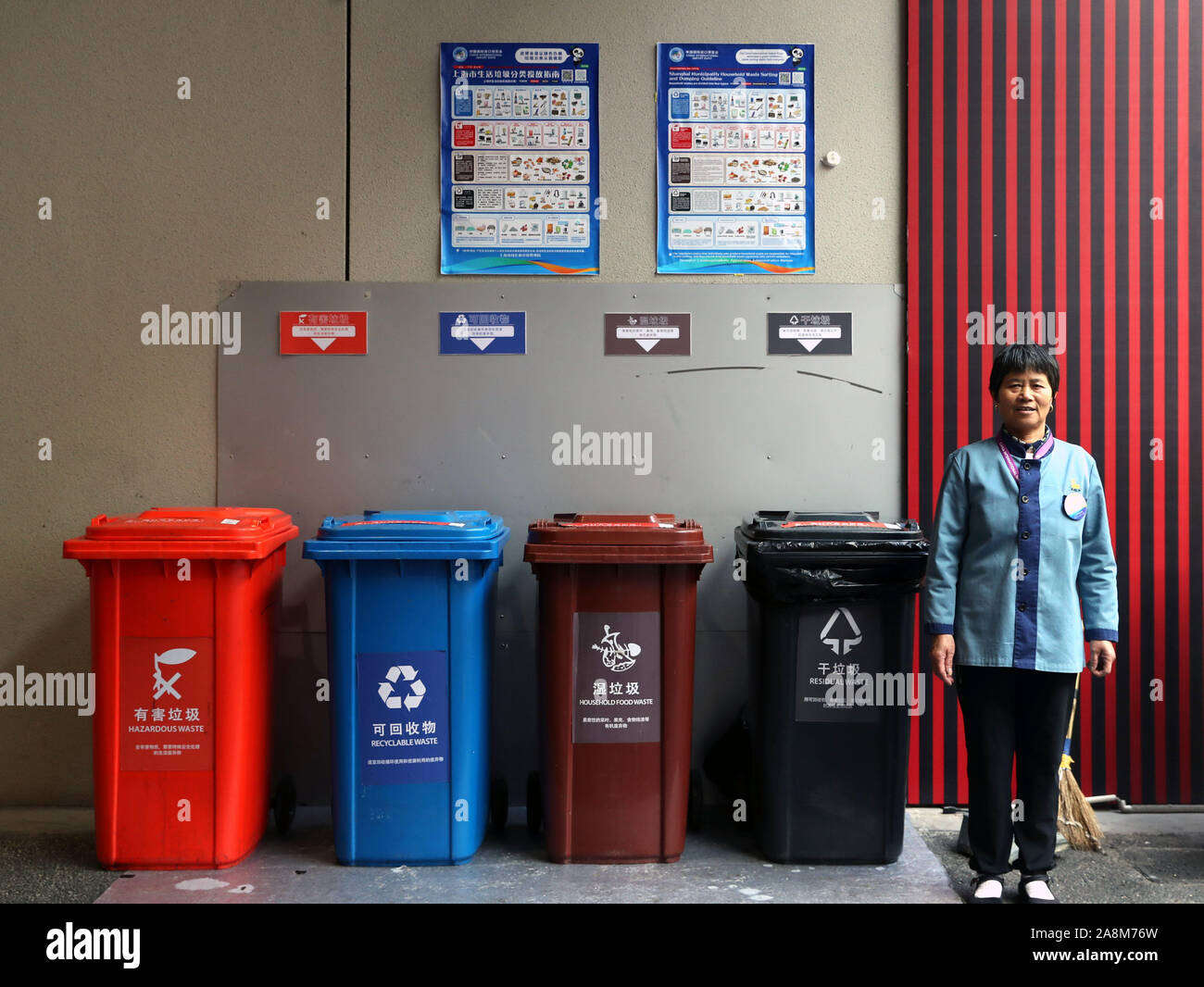 Shanghai, China. 9 Nov, 2019. Jiang Huiling, einen Bediensteten, der für die Erhaltung der Mülltonnen verantwortlich ist, steht an einem Müll sortieren Seite während des zweiten China Import Interntaional Expo (CIIE) in Shanghai, China, November 9, 2019. Fast 4.000 240-Liter Mülleimer wurden für das zweite Ciie der Expo mehr Umweltfreundliche nach Shanghai einen Satz von Vorschriften für Hausmüll Sortierung und Recycling am 1. Juli angenommen hat. Credit: Liu Ying/Xinhua/Alamy leben Nachrichten Stockfoto