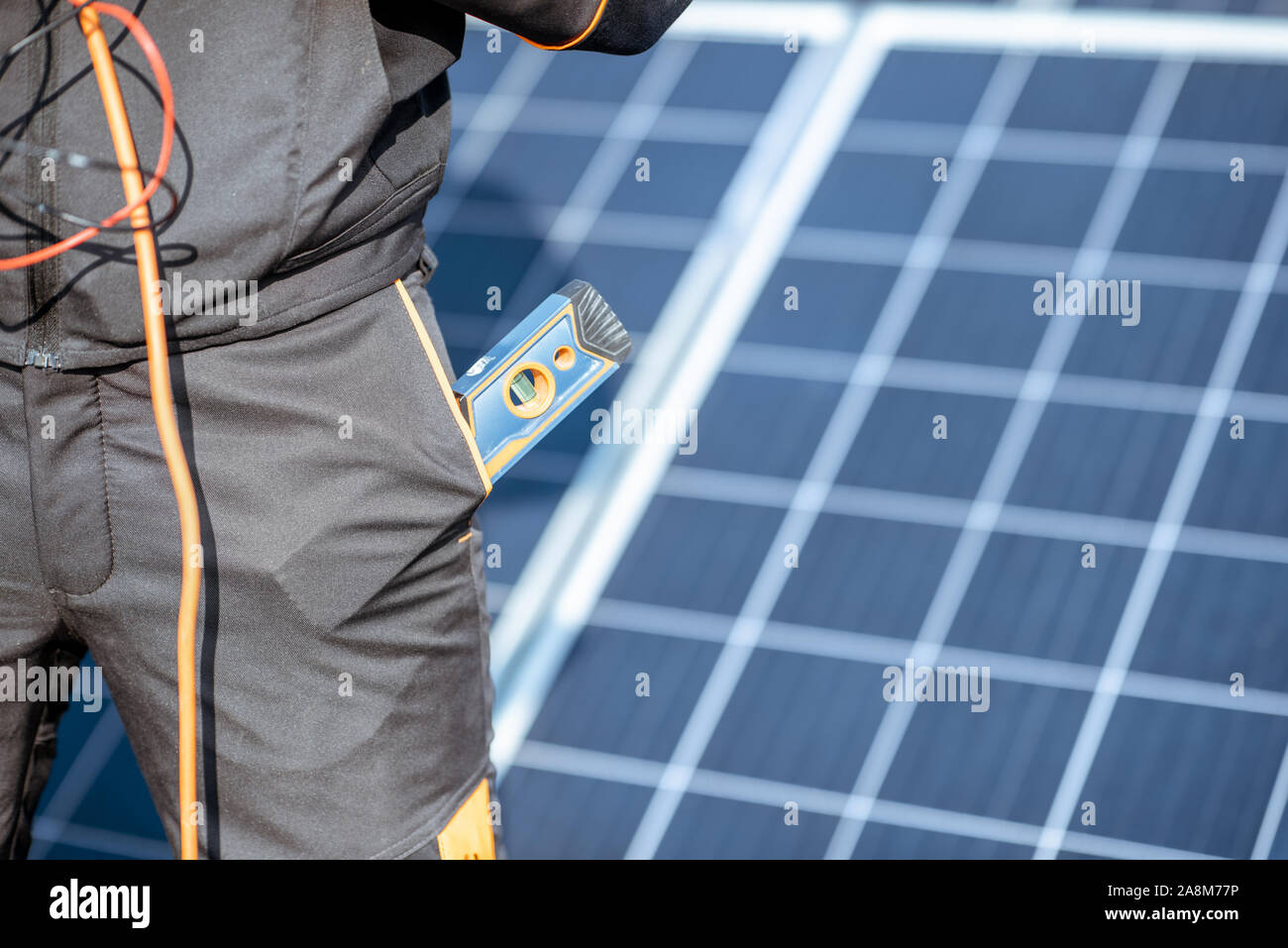 Close-up auf eine funktionierende Werkzeuge in der Hosentasche ein Arbeiter mit einer Solaranlage auf dem Hintergrund Stockfoto