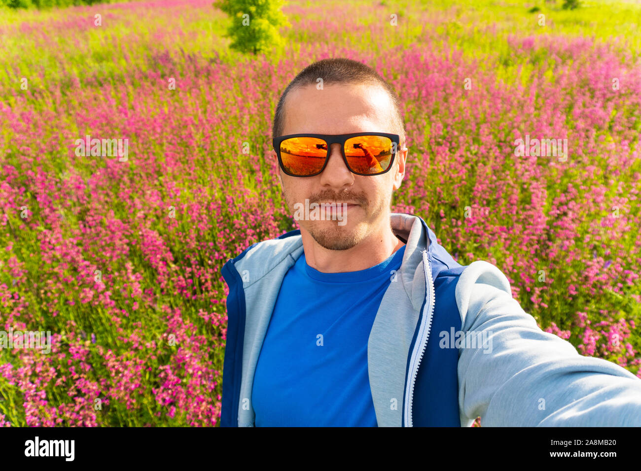 Mann in Farbe Sonnenbrille machen selfie stehen im Feld Stockfoto