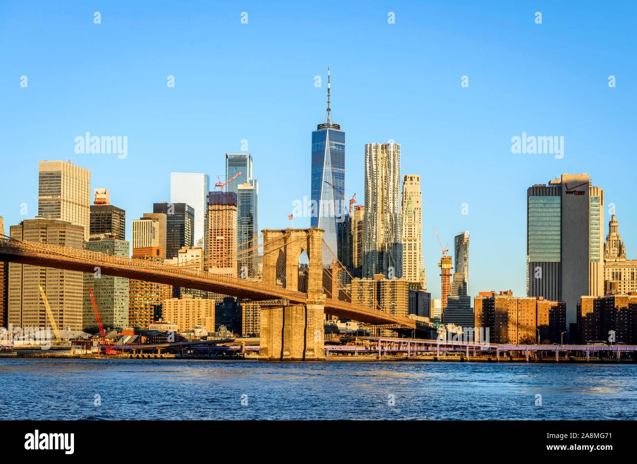 Brooklyn Bridge im Morgenlicht, Blick von der Hauptstraße über den East River Park auf die Skyline von Manhattan mit Freedom Tower oder eine Welt Stockfoto