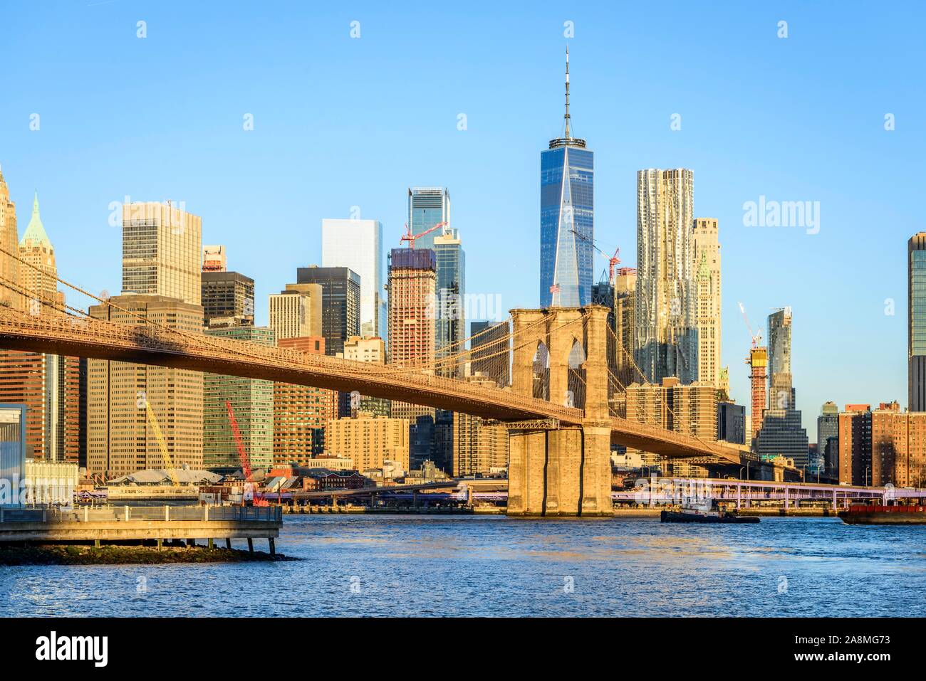 Brooklyn Bridge im Morgenlicht, Blick von der Hauptstraße über den East River Park auf die Skyline von Manhattan mit Freedom Tower oder eine Welt Stockfoto