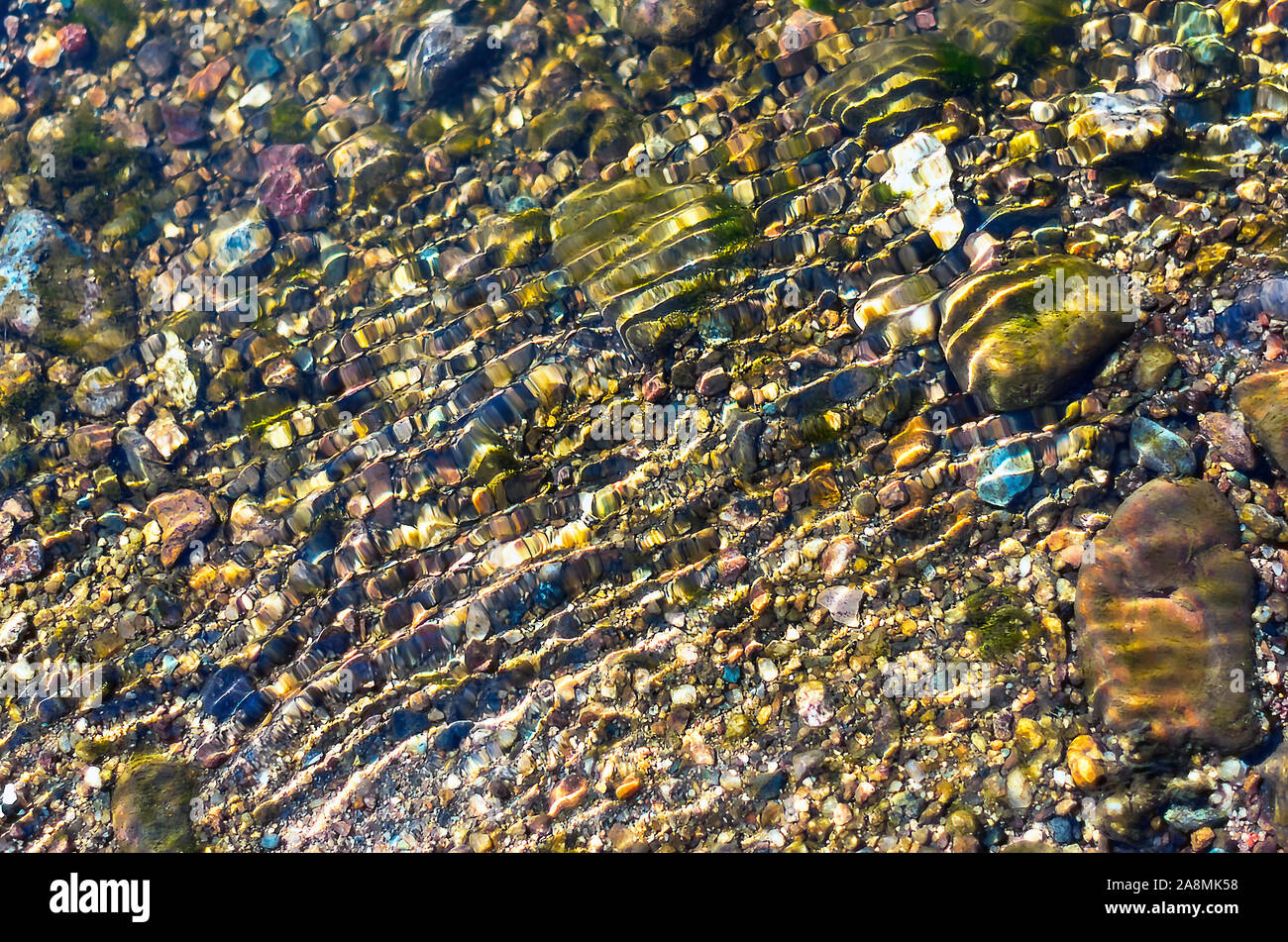 Bunte Kieselsteine im glitzernden Wasser plätschert. Organic Natural Hintergrund. Stockfoto