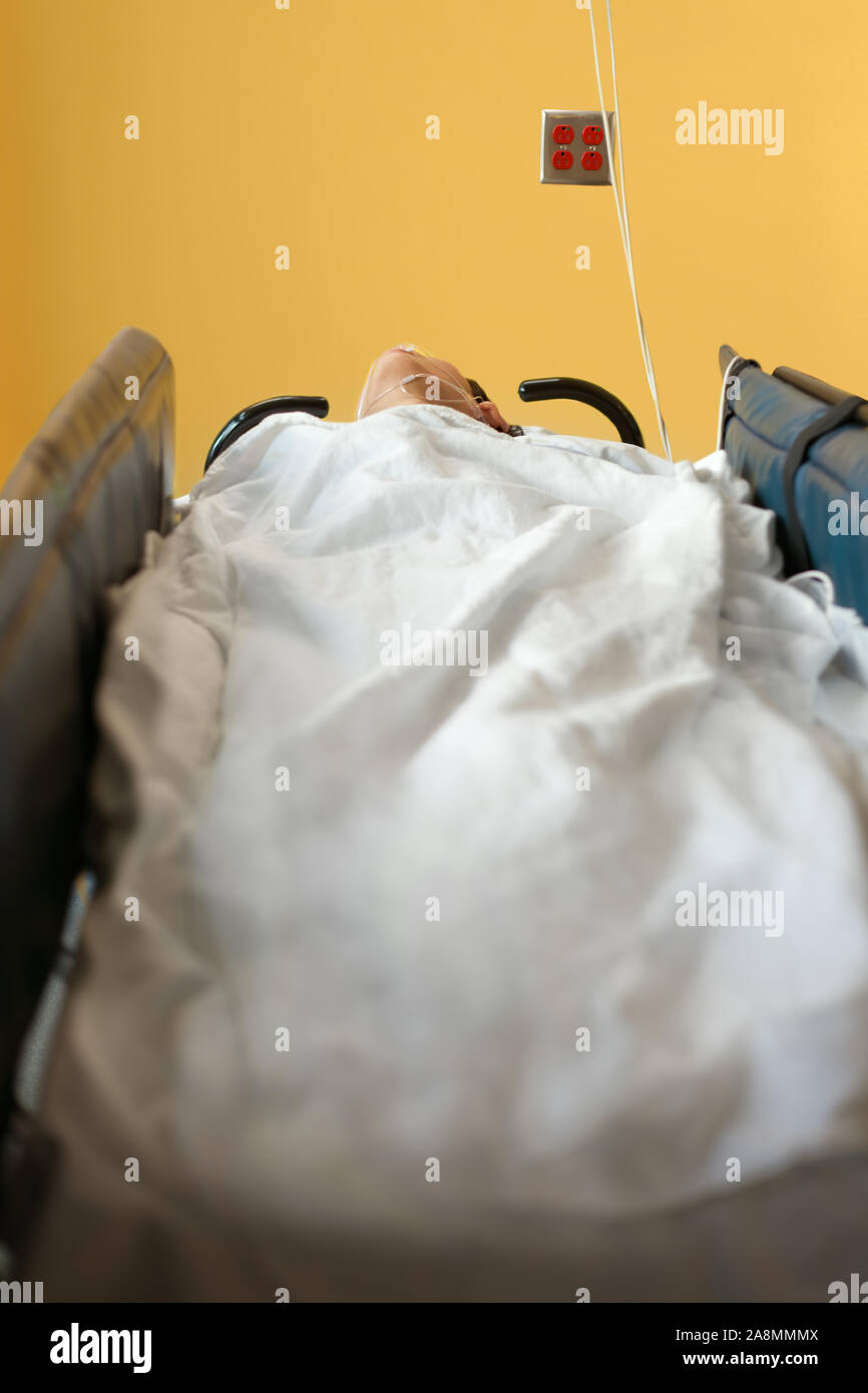 Junge 13 Jahre alt deaktiviert biracial Junge bewusstlos im Krankenhaus gurney Bett im Aufwachraum trägt blaue Patientenkittel, Atmung Rohr Dow Stockfoto