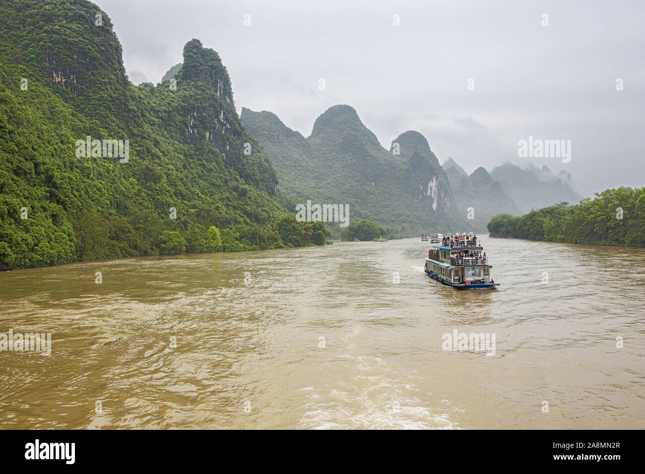 Editorial: Guilin, Guangxi, China, April 19, 2019 - River Cruise Boote im Konvoi auf dem Li River in der Nähe von Guilin navigieren Stockfoto