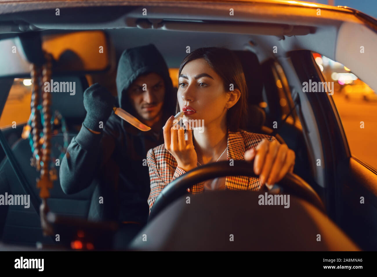 Weibliche Fahrer und Auto mit Kapuze Einbrecher mit Messer Stockfoto